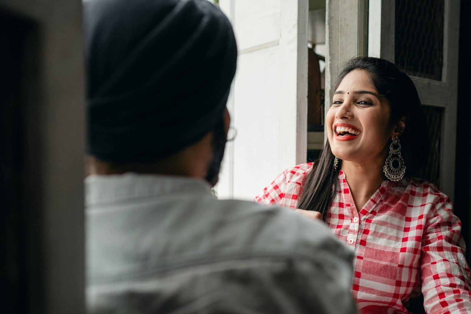 A cheerful Indian woman enjoying a casual conversation indoors with a friend.